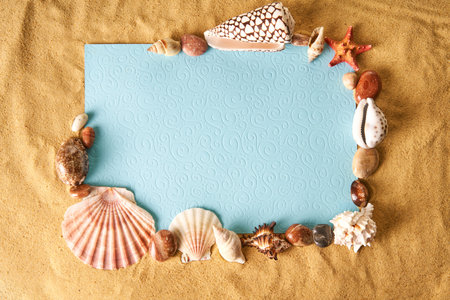 Invitation or greeting card mockup in frame of seashells and starfish on the ocean sandy beach background. Summer vacation concept, copy space. Flat lay, top viewの写真素材