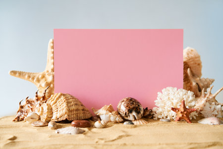 Invitation or greeting card mockup with seashells and starfish on the summer sandy beach at ocean backgroundの写真素材