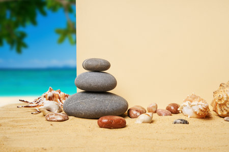 Invitation or greeting card mockup with seashells and pyramid of stones on the summer sandy beachの写真素材