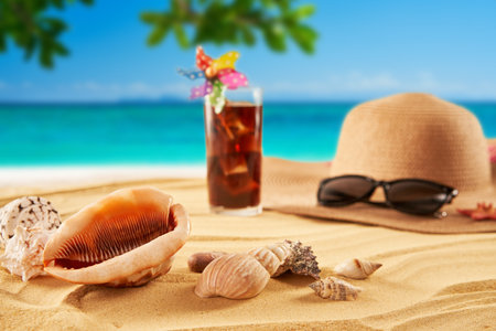 Straw hat, sunglasses and cocktail on the sand and sea background. Relax on the beachの写真素材