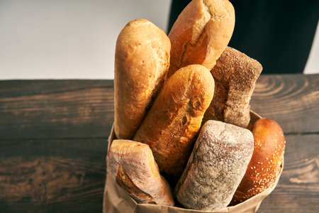 Top view of different types of french bread baguettes in paper bag over wooden backgroundの写真素材