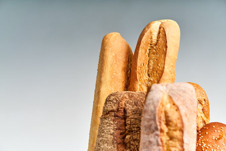 Different types of french bread baguettes in paper bag over white background with copy space
