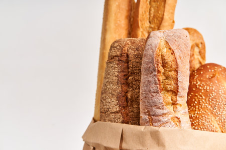 Different types of french bread baguettes in paper bag over white background with copy spaceの写真素材