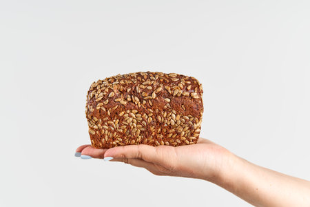 Homemade multigrain bread in woman hand over white backgroundの写真素材