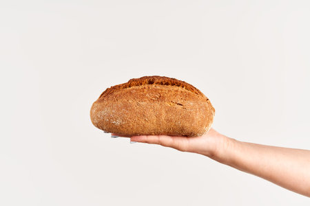 Homemade multigrain bread in woman hand over white backgroundの写真素材