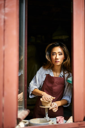 Female artist sculpts crafts with ceramic clay at her creative workshop. Mastering the art of pottery craft ceramicsの写真素材