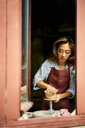 Female artist sculpts crafts with ceramic clay at her creative workshop. Mastering the art of pottery craft ceramicsの写真素材