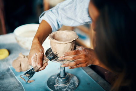Female artist sculpts crafts with ceramic clay at her creative workshop. Close-up. Mastering the art of pottery craft ceramicsの写真素材
