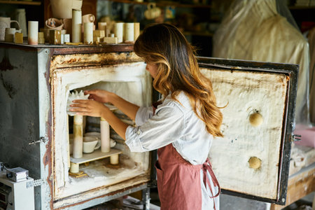 Female artist placing her ceramic clay crafts at pottery kiln. Mastering the art of pottery craft ceramicsの写真素材