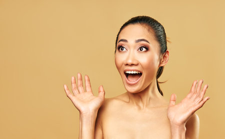 Happy excited woman isolated on beige background with copy space. Emotions, female beauty conceptの写真素材