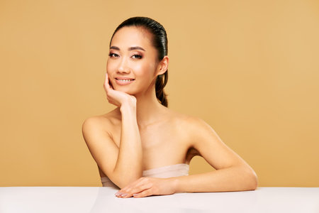 Beauty portrait of smiling young woman with healthy skin posing over beige background. Fashion, make-up, self care conceptの写真素材