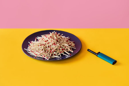 Pile of wooden matches on plate with lighter over pink yellow background. Danger, risk conceptの写真素材