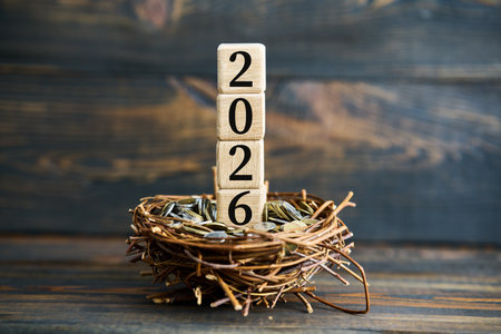 Wooden blocks with 2026 in nest filled with coins. Financial growth concept