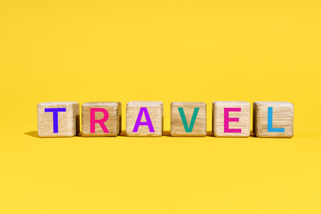 The word TRAVEL on wooden blocks on vibrant yellow background with colorful letters.の写真素材