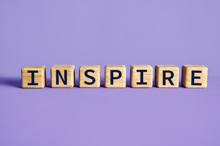 Wooden blocks spelling the word INSPIRE purple background. Motivation conceptの写真素材