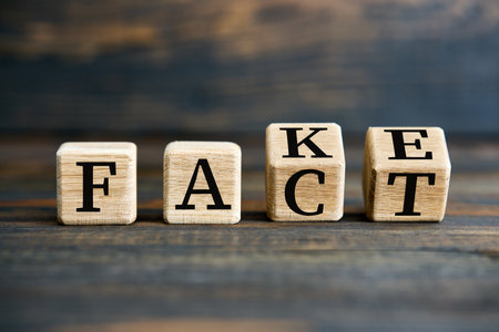 Flipping wooden cube blocks with FAKE to FACT text on wooden background. Manipulation conceptの写真素材