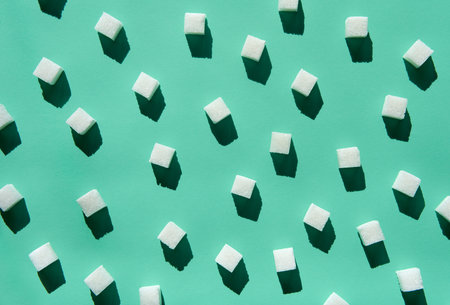 Minimal flat lay of white sugar cubes arranged randomly on green pastel backgroundの写真素材