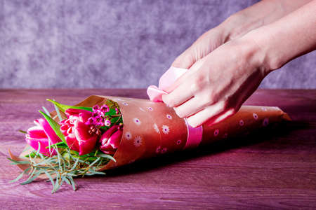 florist makes a bouquet with tulips in Kraft paper