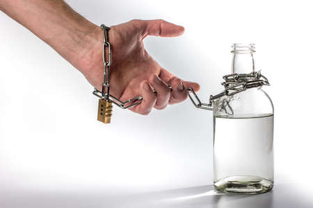 hand tied metal chain with bottle on white background. alcohol dependenceの写真素材