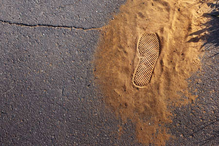 handful of sand on the pavement with a boot markの写真素材