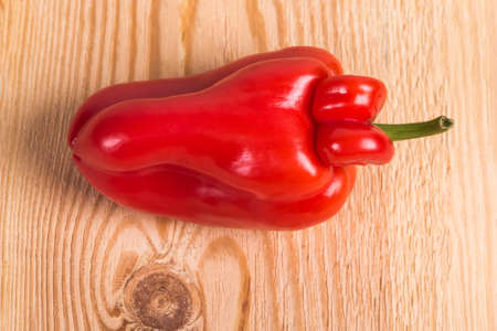 Trendy ugly organic farm vegetable - red sweet bell pepper with mutation parts on wooden background....
