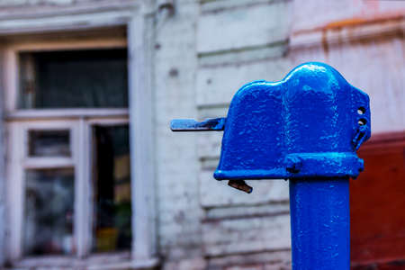 old blue water column on the background of an old wooden house
