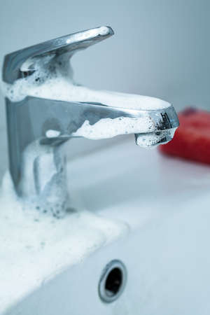 cleaning the dirty tap and sink with foam spongeの写真素材