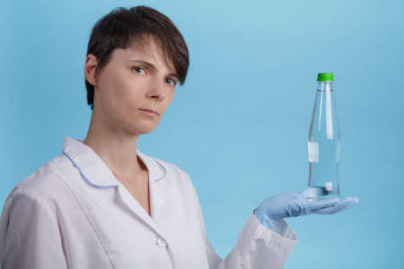 portrait of a young Caucasian girl holding a bottle of clean water as an idea of healthy nutrition. doctor's recommendationの写真素材