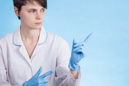 doctor a girl in a white coat and gloves points to the side. preparation for the writing of the textの写真素材