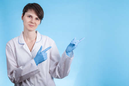 doctor a girl in a white coat and gloves points to the side. preparation for the writing of the textの写真素材