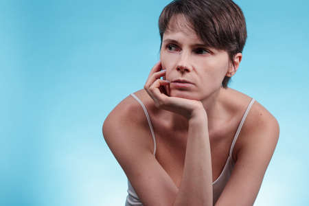 Young woman in a thoughtful pose on blue backgroundの写真素材