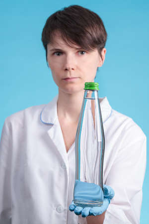 portrait of a beautiful woman doctor who holds a bottle of clean drinking water as a healthy food conceptの写真素材