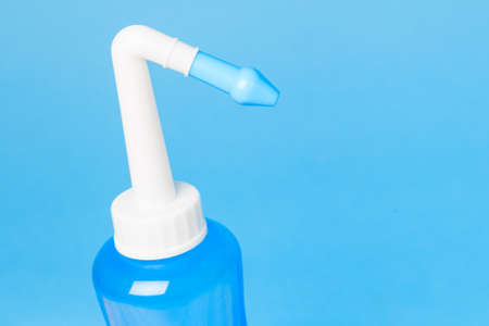 blue water pulse nasal wash bottle on a blue background, nasal irrigation conceptの写真素材