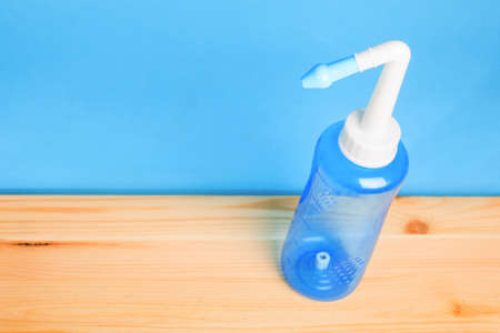 blue water pulse nasal wash bottle on a wooden table, nasal irrigation conceptの写真素材