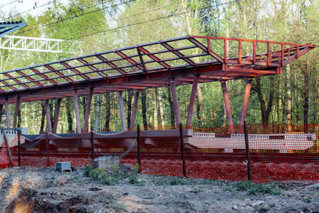 Construction of a new waiting platform for the railway station. Metal structure of the canopy over the station. Green forest in the background.の写真素材
