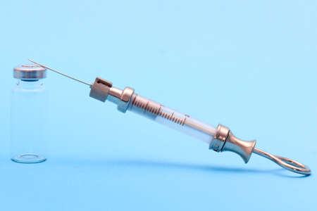 antique syringe made of metal and glass and phial on a blue background. free space for text....