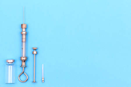 antique syringe made of metal and glass on blue background. free space for text. copyspaceの写真素材