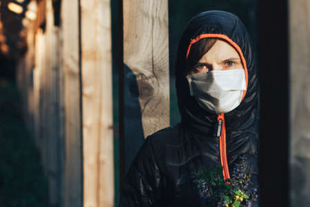 portrait of a girl in a medical mask and hood, who walks in the woods. concept of wearing a medical...
