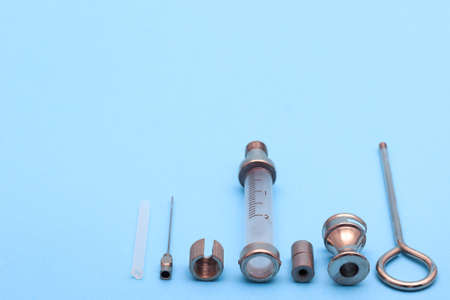 antique syringe disassembled into details on a blue background