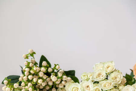 flowers and greens on the edge of a ligth white wooden tableの写真素材