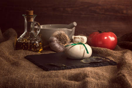 Burrata, Burata or Fresh Mozzarella Cheese with Tomato, Olive Oil, Basil and garlic on dark Backgroundの写真素材