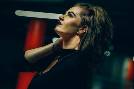 Beautiful glamour and fashionable portrait. She is possing in a dark room with background lights.の写真素材