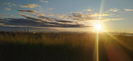 beautiful sunrise panorama with greenery and mountains in silhouette and beautiful sun rays and dramatic cloudsの写真素材