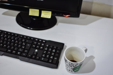 work table with keyboard and monitor out of focus and a cup of coffee and note stickers on the screenの写真素材