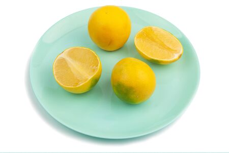 two whole yellow-green grapefruit and two halves on a turquoise plate on a white background. Isolateの写真素材