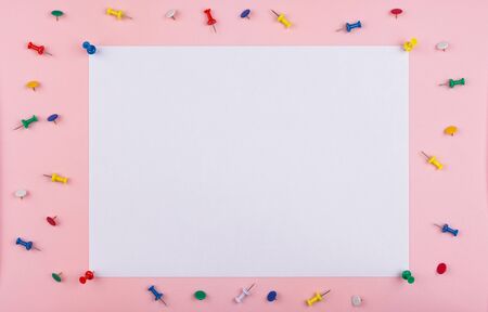 white sheet fastened with clerical multi-colored buttons on a pink background. Multicolored stationery buttons are scattered on the backgroundの写真素材