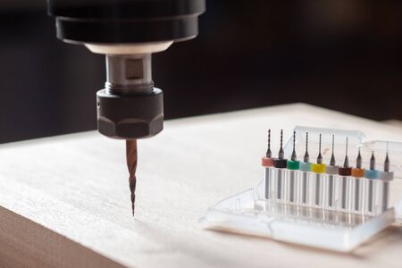 spindle with a milling machine cnc machine over a wooden surface, on the right is a box with ten...