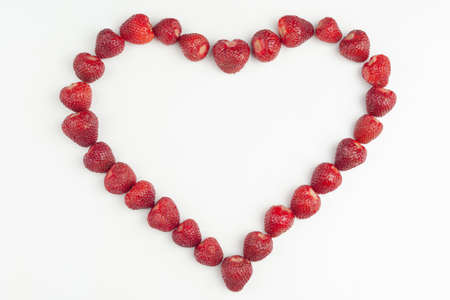 heart is laid out of strawberries on a white background