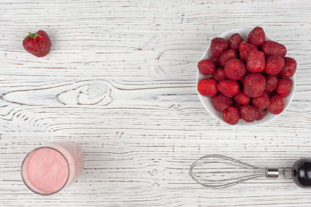 strawberry cocktail, blender and plate with strawberries on a white wooden background, view from aboveの写真素材