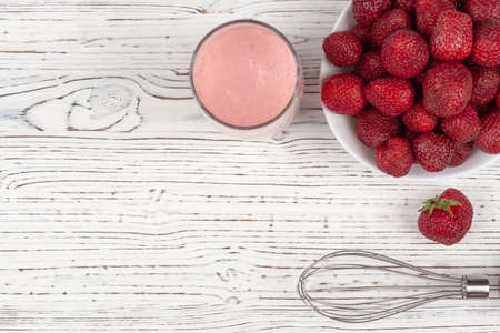 strawberry cocktail, blender and plate with strawberries on a white wooden background, view from aboveの写真素材